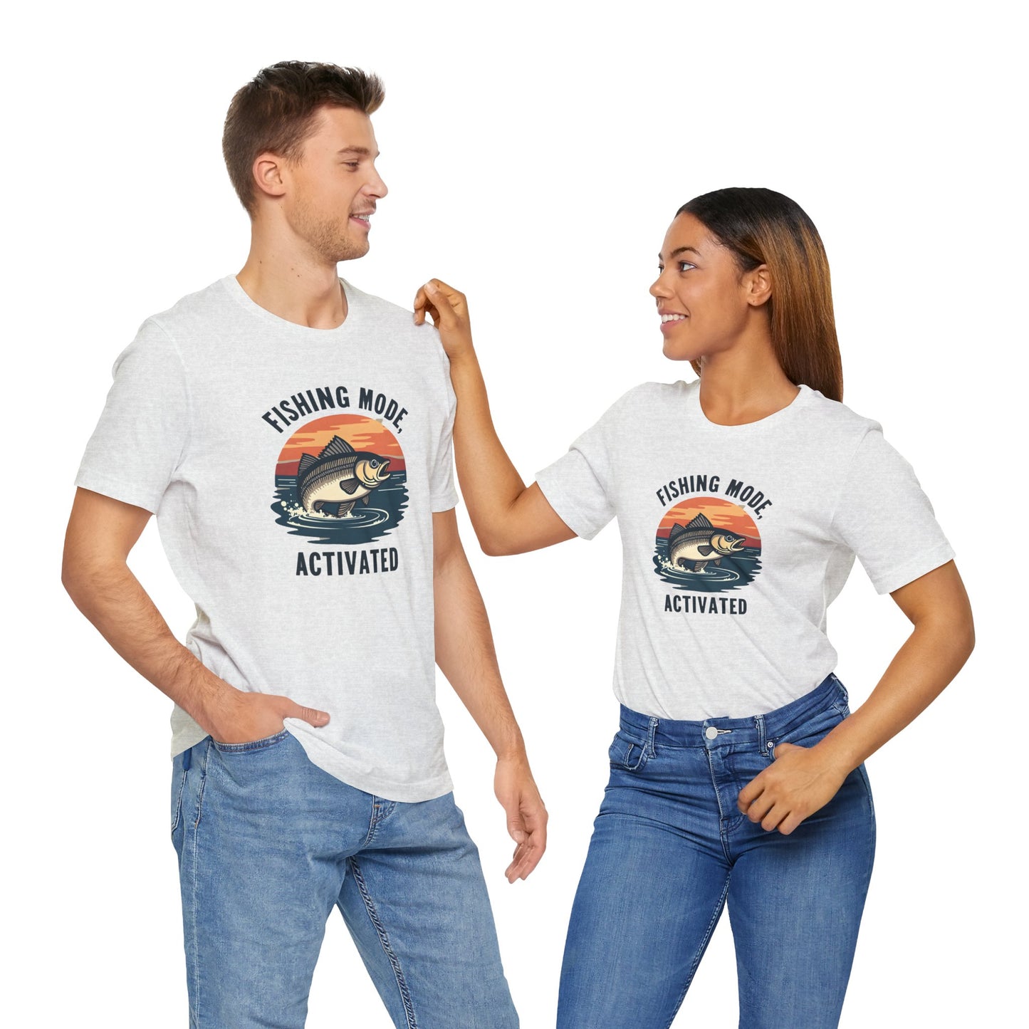 A man and woman, each in blue jeans and a crisp white Printify Fishing Mode Activated Tee for Anglers, exchange smiles. Their unisex jersey short sleeve t-shirts feature a fish graphic and are made from soft Airlume cotton, all set against a clean white backdrop.