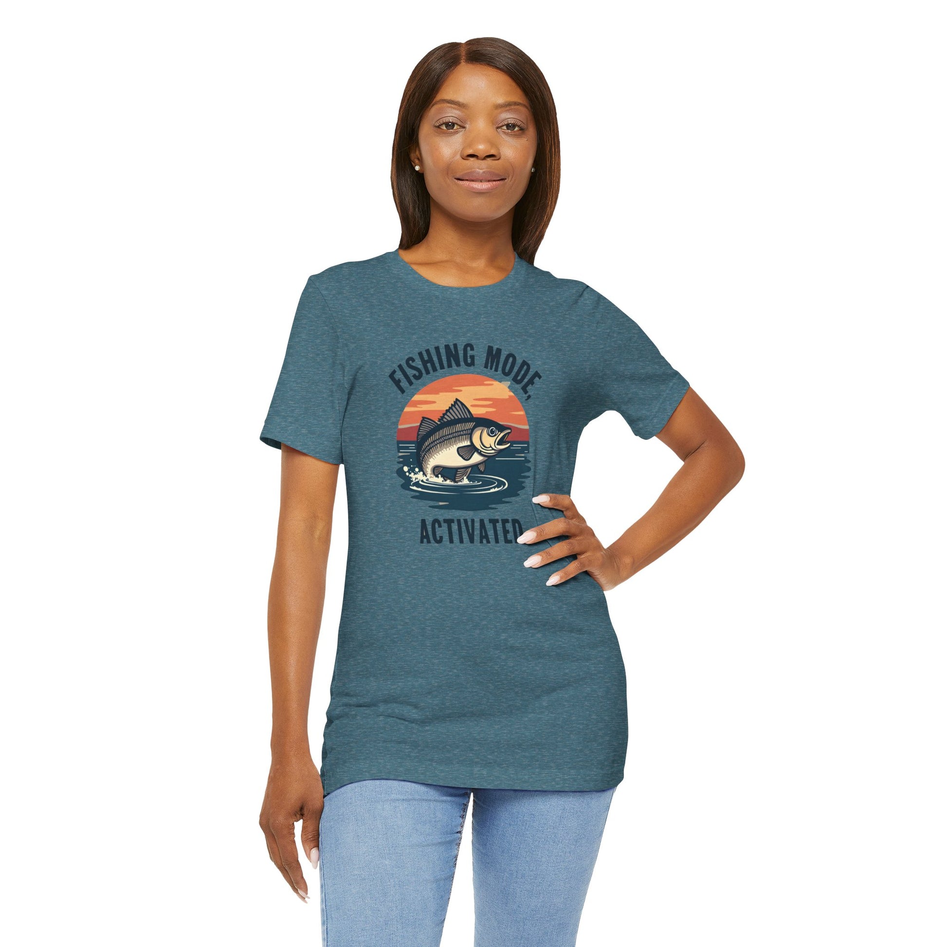 A person wears a blue unisex jersey t-shirt by Printify, featuring a fish jumping against a sunset with the text FISHING MODE ACTIVATED. Made from soft Airlume cotton for ultimate comfort, its called the Fishing Mode Activated Tee for Anglers.
