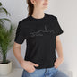 Wearing a Auckland Skyline Unisex Tee by Printify, this person sports a black jersey tee with a white cityscape outline and AUCKLAND NEW ZEALAND text. 