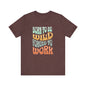 The Born to Be Wild Unisex Jersey Tee by D&B Apparel is a brown shirt made from soft Airlume cotton, featuring a colorful retro design with the text Born to be Wild, Forced to Work in pastel blue, orange, and yellow. Its perfect for adventurers seeking comfort and flair.
